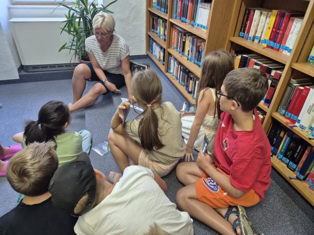 Kinder hören der Erklärung der Bibliothekarin zu