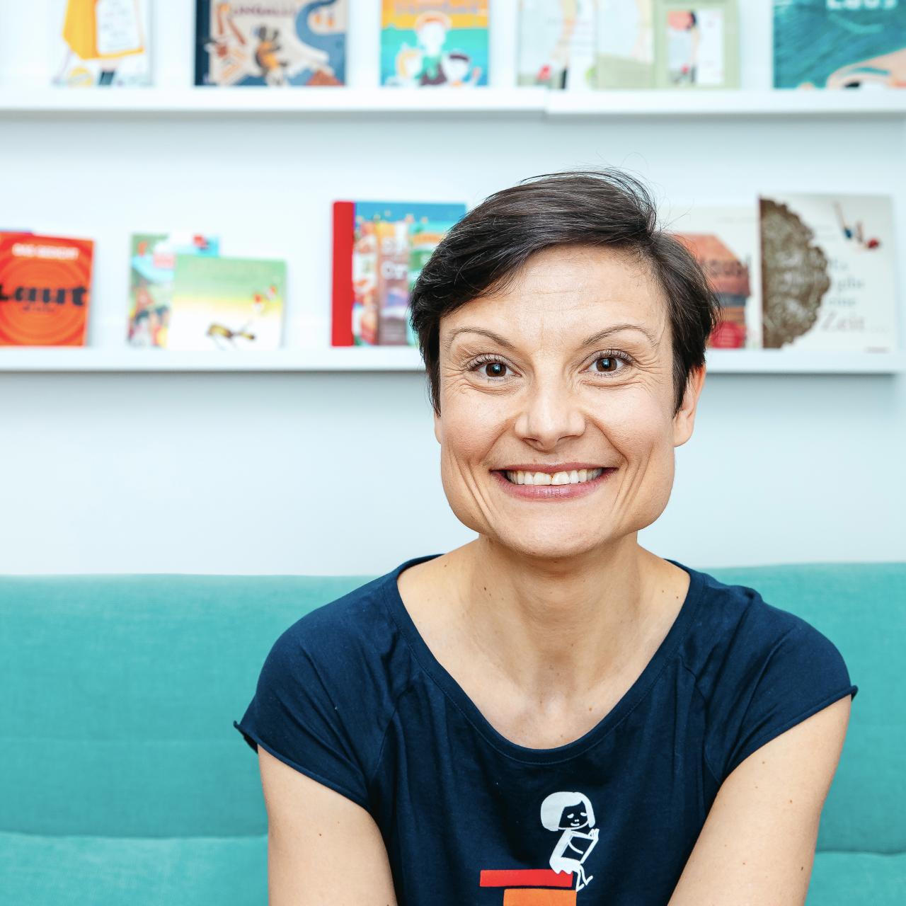 Frau auf Sofa sitzend vor Bücherregal